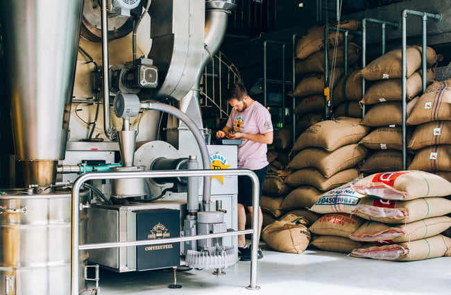 Man standing amongst bags of coffee beans.