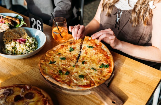 A woman pulls the pieces apart of a margherita pizza at hello RANGER, Wānaka.