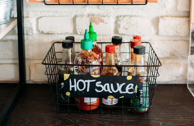 A small black wire basket of hot sauces.