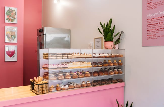 A close up of sweet treats and donuts inside a glass cabinet.