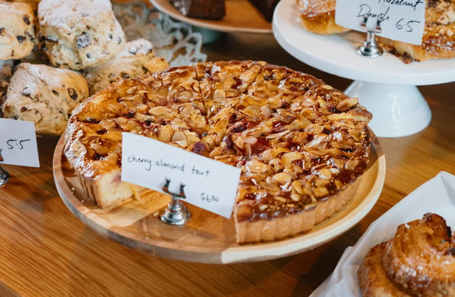Cherry and almond tart amongst other sweets displayed for sale.
