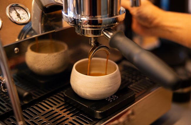 Creamy shot of espresso pouring out of coffee machine