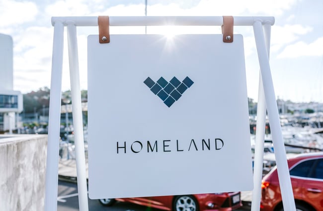A close up of a white sign that says 'Homeland'.