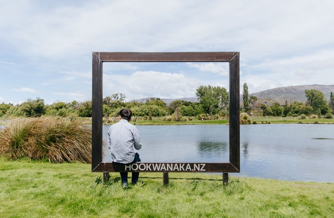 A man sitting next to the lake fishing.