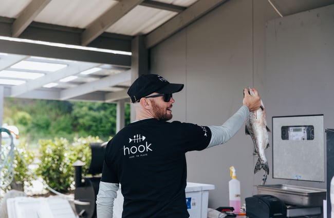 A chef holding up a large fish.