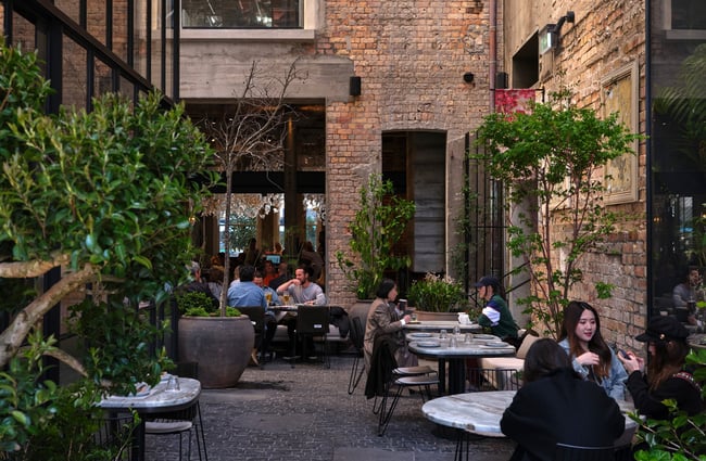 Customers dining at tables against exterior brick walls of Hotel Britomart.