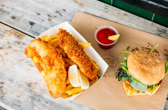 A flatlay of fish and chips on a wooden table.