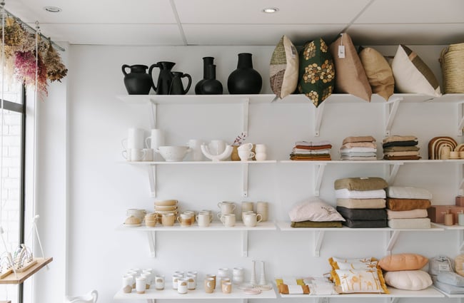 Shelves filled with homewares including pottery and cushions.