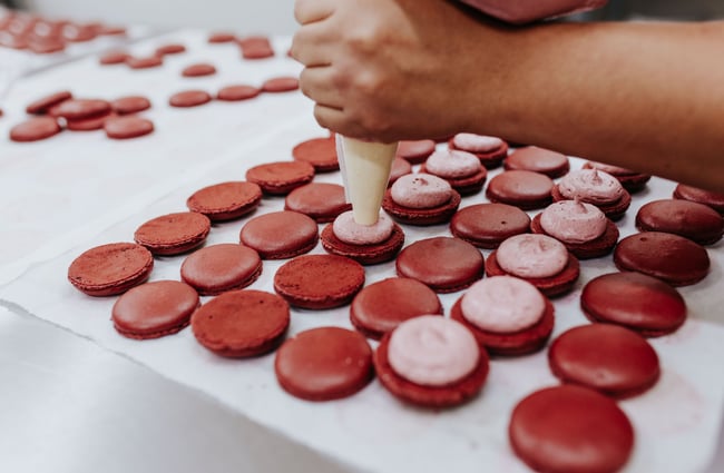 Woman making rows of macarons at J’aime les macarons in Christchurch.