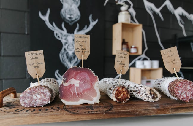Cured meats on a wooden chopping board for tasting.