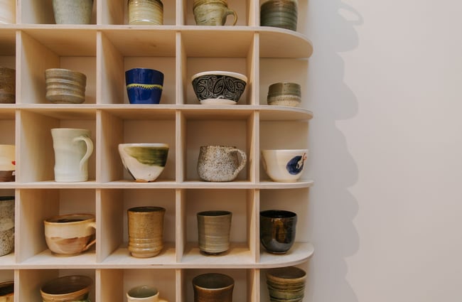 Ceramic cups on a shelving unit at Kiln Gallery.