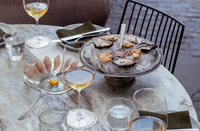A plate of seafood and glasses of wine on a marble table.