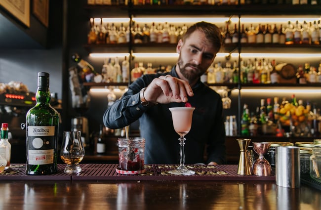 Barman placing a petal on a cocktail at Kismet.