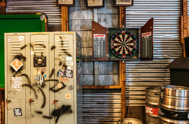 A dart board and graffitied lockers on a wall inside Last Place Bar Hamilton.