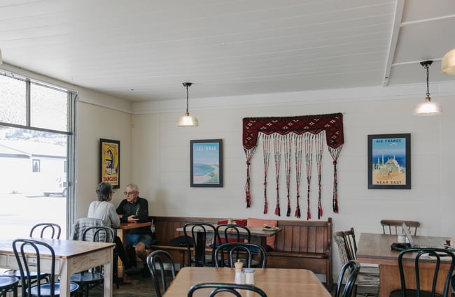 The interior view of the Little Dove Cafe, where two people are sitting at a table in the corner.