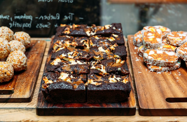 A close up of brownies in a glass cafe cabinet.