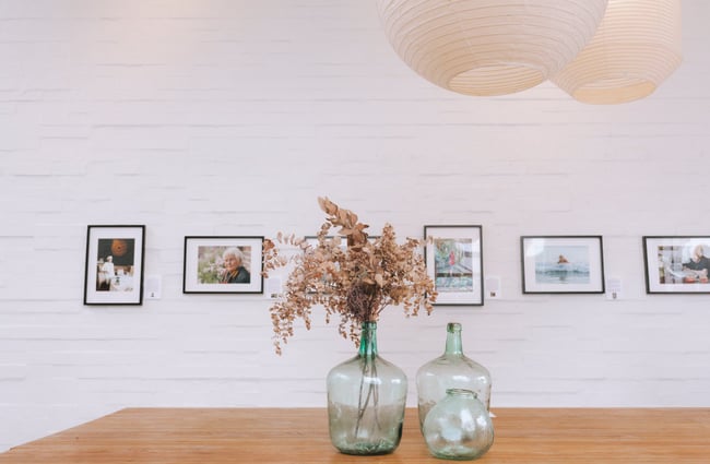 Photography framed on the wall with dried flowers in glass jars on the table below at Little Rosie, Auckland.