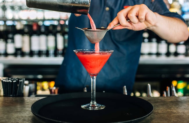 Close up of cocktail being made by bartender in denim shirt.