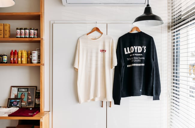 Lloyds t-shirt and jumper on a wall.