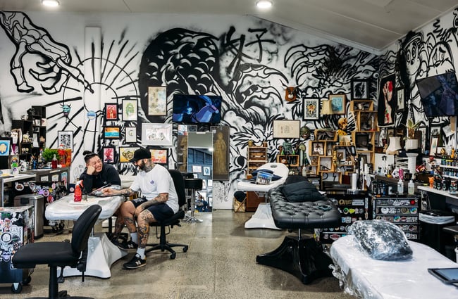 Two men planning a tattoo inside Good Honest Tattoos studio.