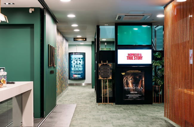 Posters on display on green walls in cinema.