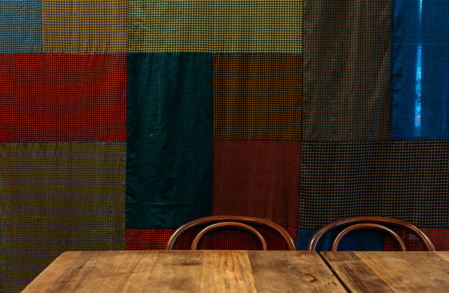 Checked sarongs hanging behind a table and chairs at Mabel's, Wellington.