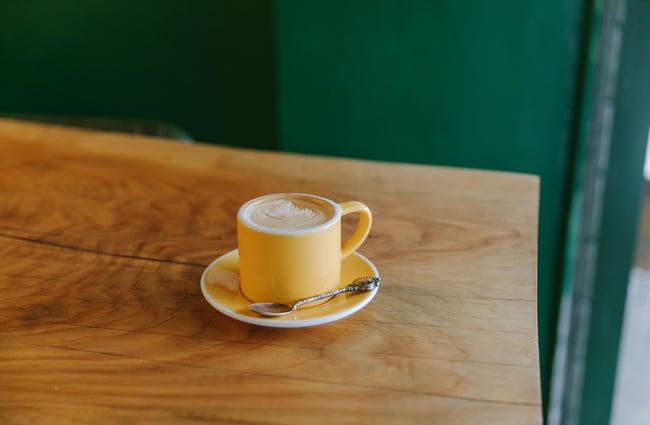 A close up of a flat white in a yellow cup.