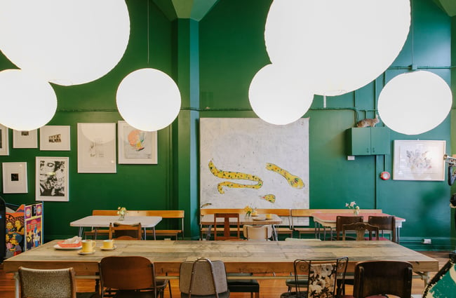 Large tables with low hanging lights set against dark green walls.