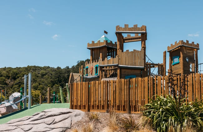 A large wooden fort at a playground on a sunny day.