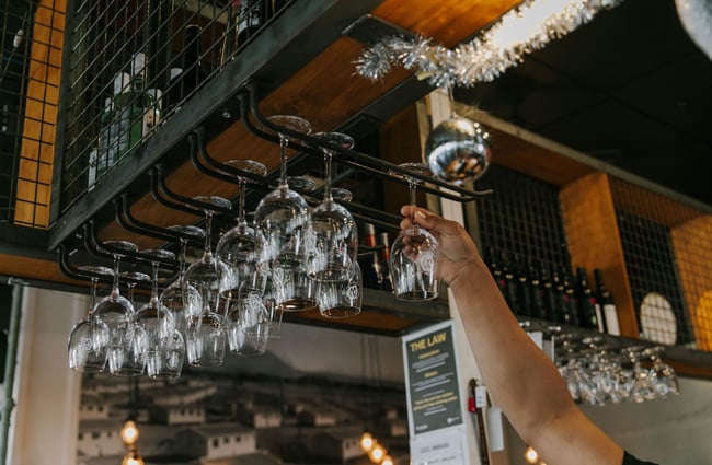 Hand reaching up to glasses above the bar at Ministry of Works, Twizel.
