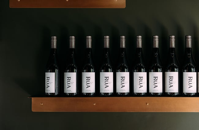 Bottles of wine bottle lined up on a shelf.