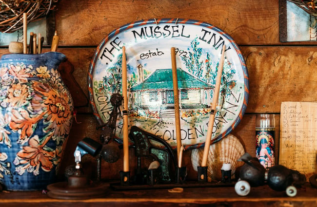 A 'The Mussel Inn' blue and white plate above a fireplace.