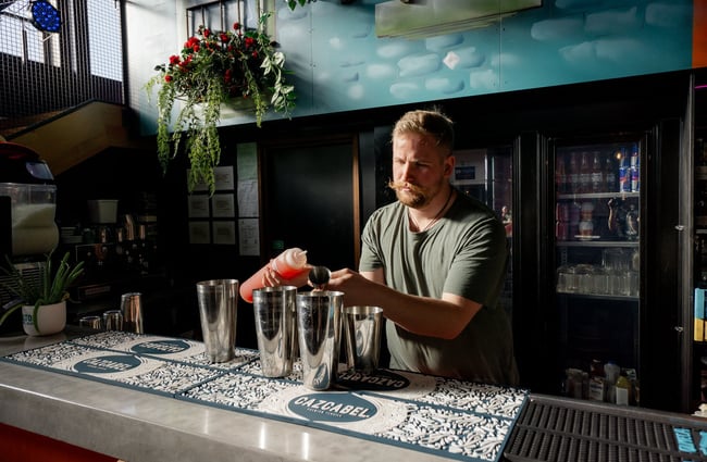 A close up of a mixologist making a cocktail at a bar.