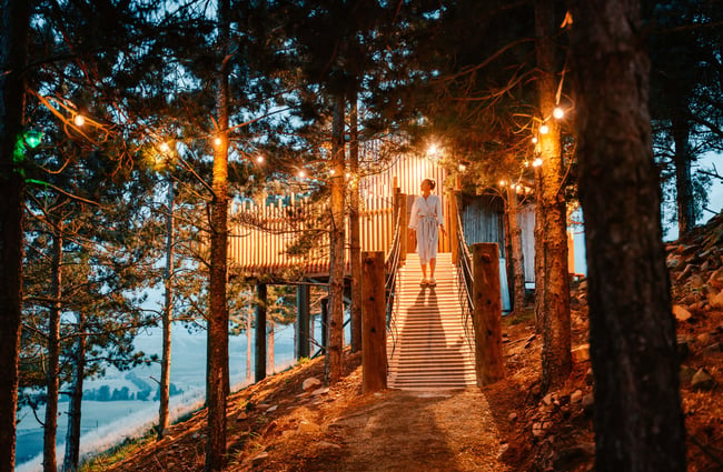 A woman walking down a brightly lit staircase at dusk.