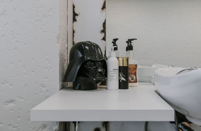 Darth Vader mask next to hair styling products at New City Barbers in Christchurch.