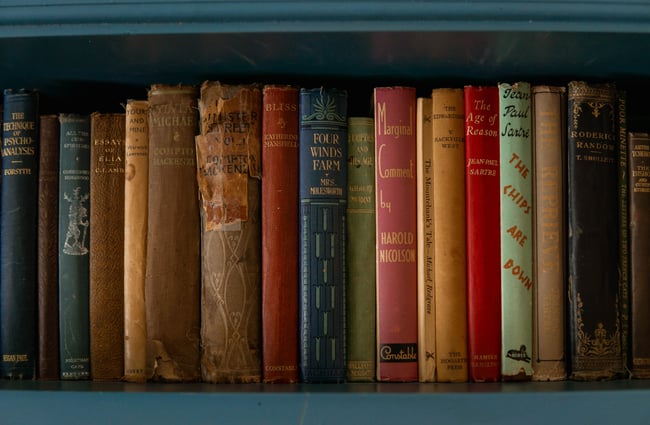 A close up of some very old books on a shelf.