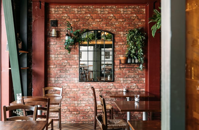 A covered outdoor area in a bar with a brick wall.