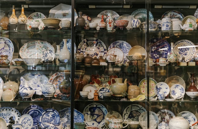 A glass cabinet full of Chinese plates and cups.