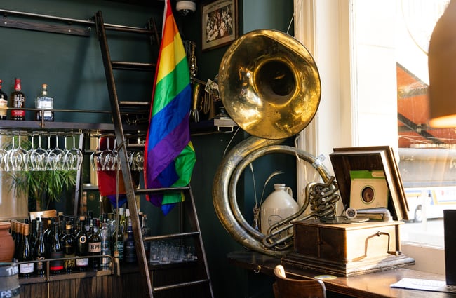 Close up of gold tuba, Pride flag and vintage turntable next to bar at OGB