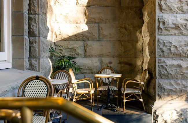 Charming outdoor nook at OGB with classic French bistro chairs against a solid stone wall