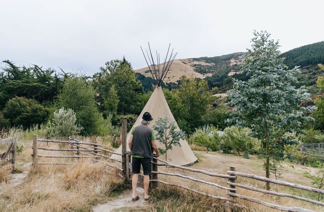 A man walking towards a teepee at Okuti Garden in Little River.