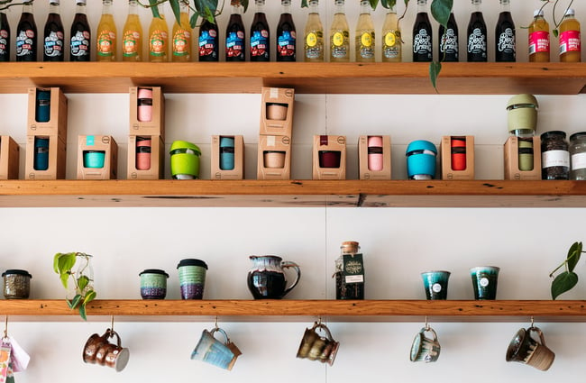 Reusable cups on display on wooden shelves.