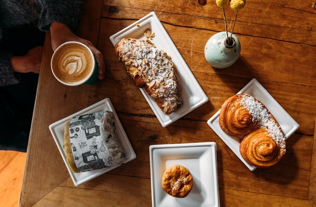 A flatlay of pastries on a wooden table on a sunny day.