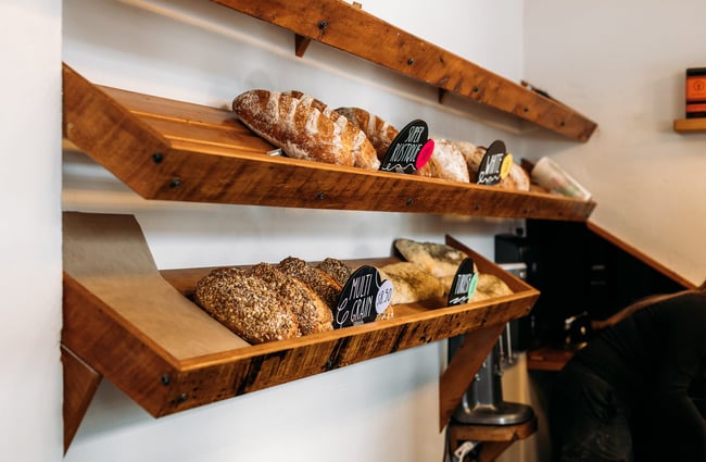 A close up of sourdough loaves on wooden shelves.