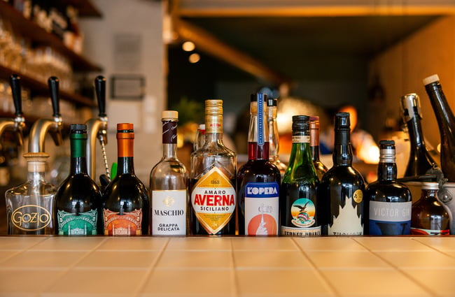 Liquor bottles lined up on a bar.