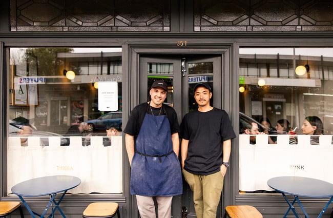 Two men standing outside a restaurant.