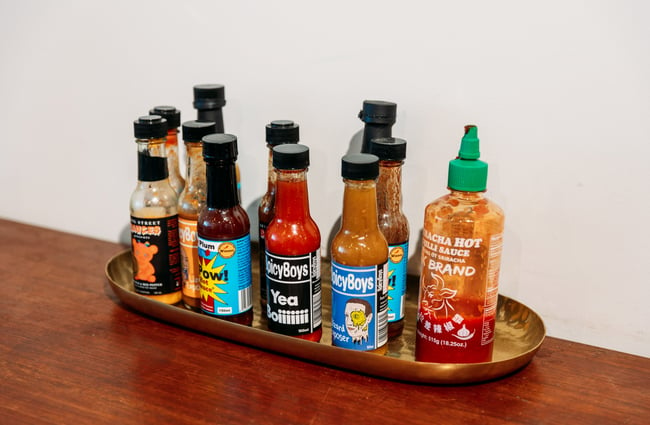 Bottles of hot sauce on a wooden bench.