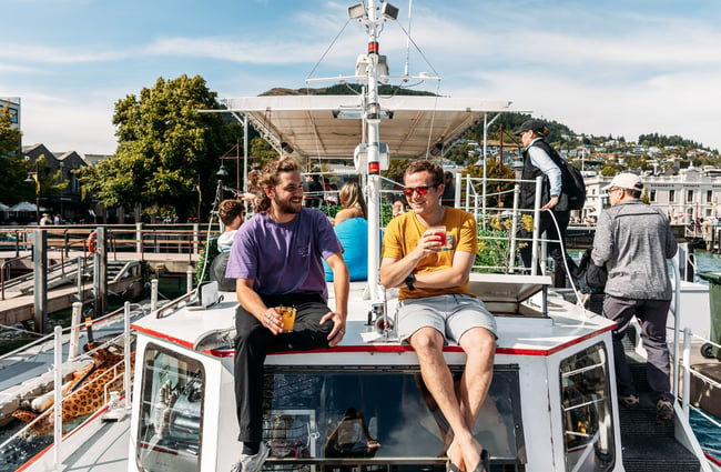 Two men sitting on a boat drinking cocktails.