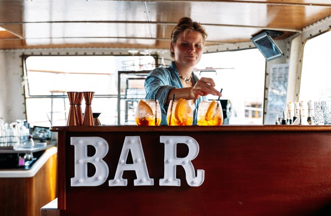 A woman making drinks behind a bar on a boat.