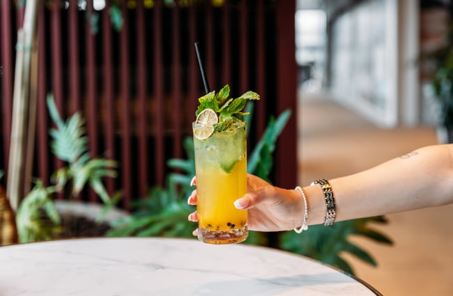 A hand holding a yellow cocktail.